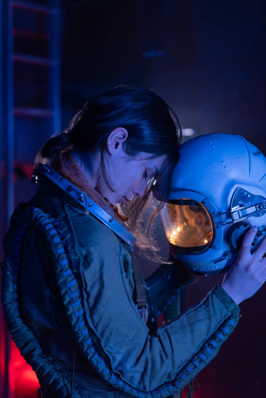 A futuristic, dimly lit laboratory in space, with astronauts in advanced suits tending to glowing bioreactors and sophisticated medical equipment. Stars are visible through a panoramic window.
